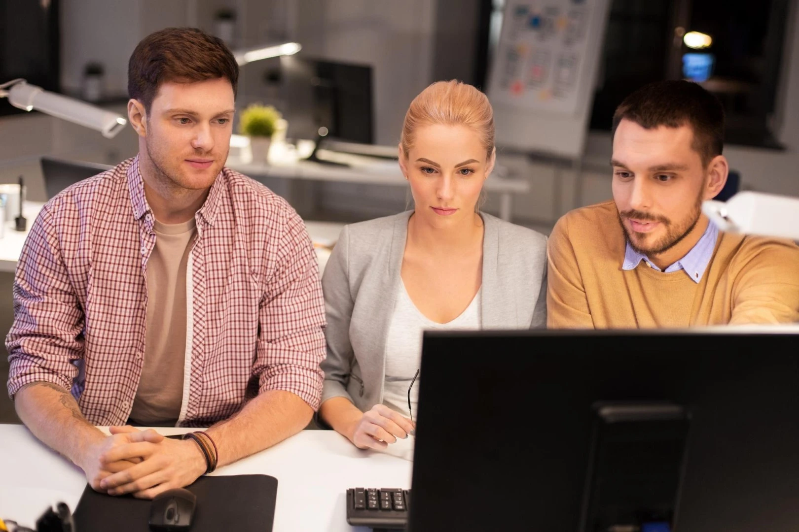 3 employés travaillent sur un ordinateur pour assurer la maintenance informatique d'une entreprise en Belgique